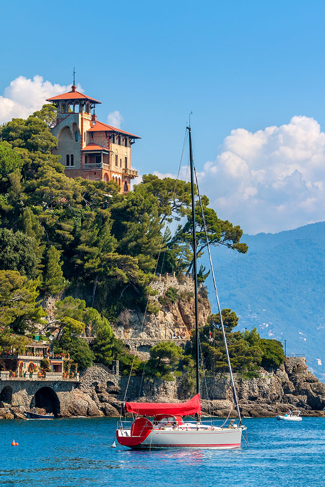 Yacht on the sea and beautiful old villa on the cliff of Portofino