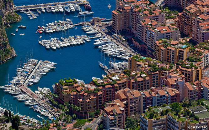 Close-up cityscape photograph of the Principality of Monaco and bordering Beausoleil. The image illustrates the densely populated and constructed city on the Côte d’Azur with its red rooftops and narrow streets. Fontvieille Cluster