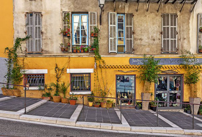 Pedestrian walkway along house with small gift shop in old Nice