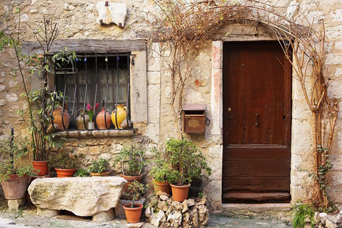 Street garden and potted plants in front of windows and doors in the quaint little French hilltop village of Saint-Paul de Vence, Southern France, a Heritage Site